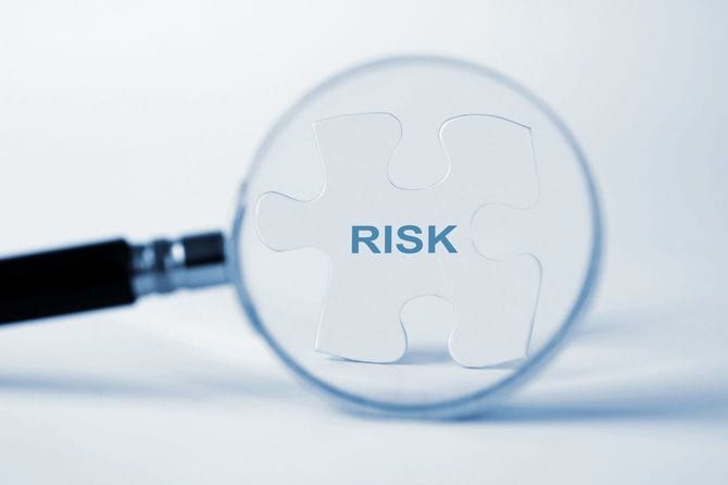 拡大鏡に映し出される、「リスク」と書かれたパズルのピース