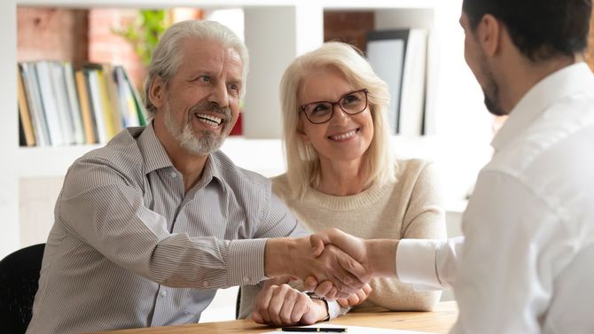 笑顔の老夫婦がエージェントと握手を交わす