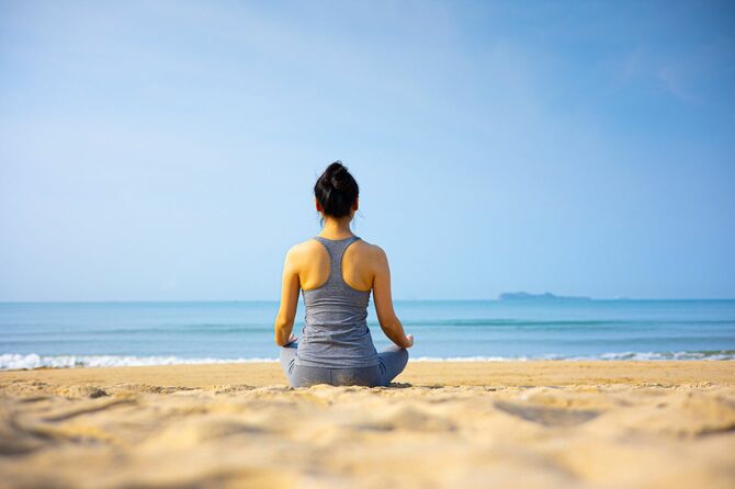 ビーチで瞑想する女性
