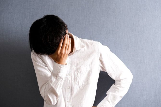 壁によりかかり、顔を覆う男性