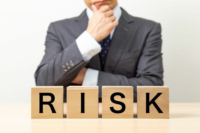 「RISK」と書かれたブロックと、ビジネスマン