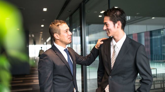 金融街のビルで2人のビジネスマンが立ち話