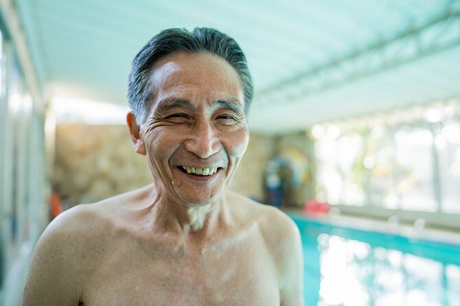 プールサイドに立つ笑顔の高齢男性