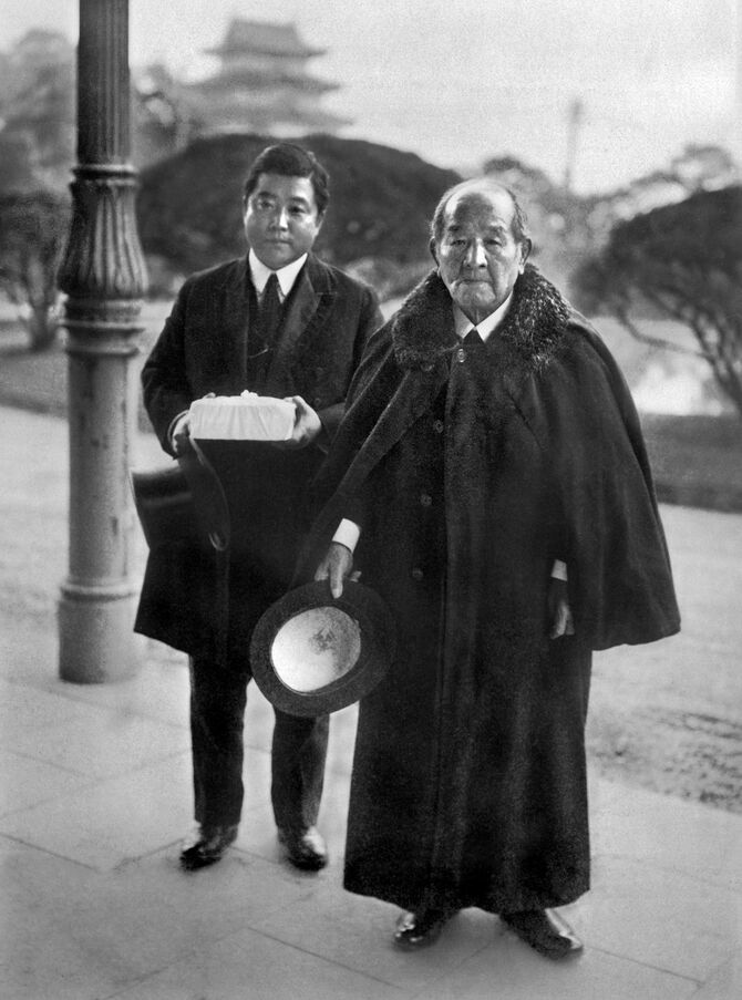 昭和天皇との会食を終え退出した渋沢栄一（右）。左は付き添った孫の渋沢敬三＝1929年12月19日、宮内省玄関前（日本電報通信社撮影）