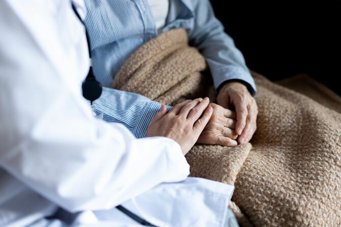 老婦人の手をさすり、励ます訪問医