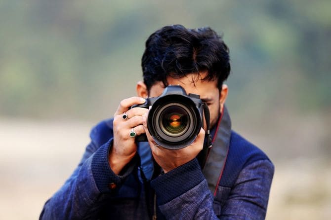 屋外で一眼レフカメラを構えてシャッターを切るプロのカメラマン