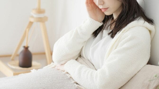 朝、ベッドで悩む女性