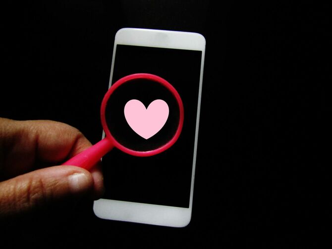 スマートフォンに映るハートマークをルーペで見る手