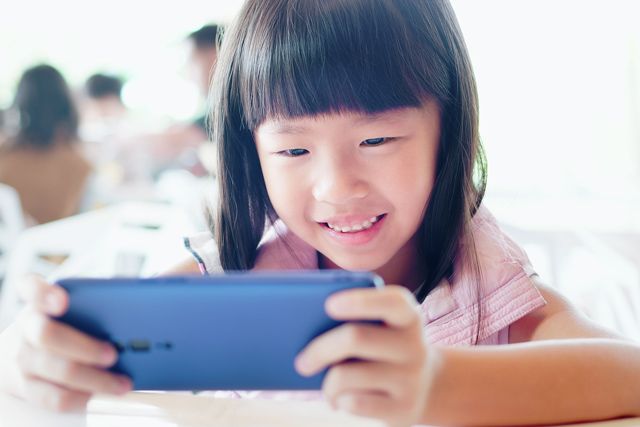 女の子は、ビデオを見たり、携帯電話で楽しくモバイルゲームをプレイ