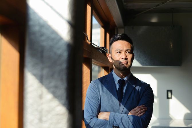 窓辺で腕を組む真剣なビジネスマン