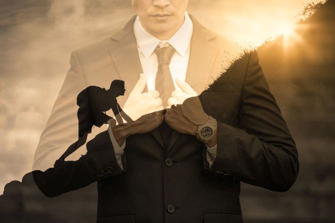 山を登る男性とその後ろに映るスーツのビジネスマン