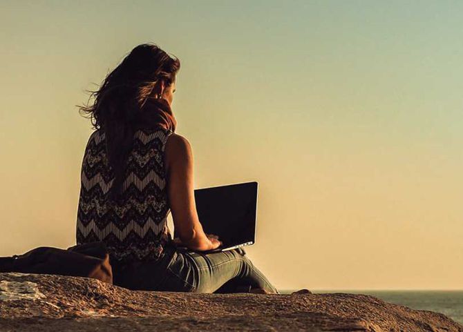 野外でラップトップを開く女性