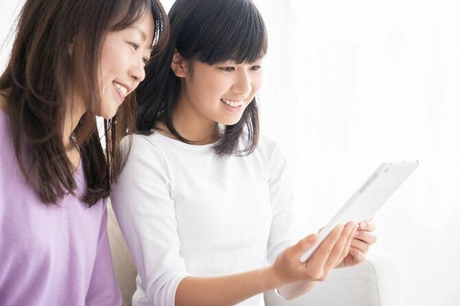 一緒にスマートフォンを見る母と娘