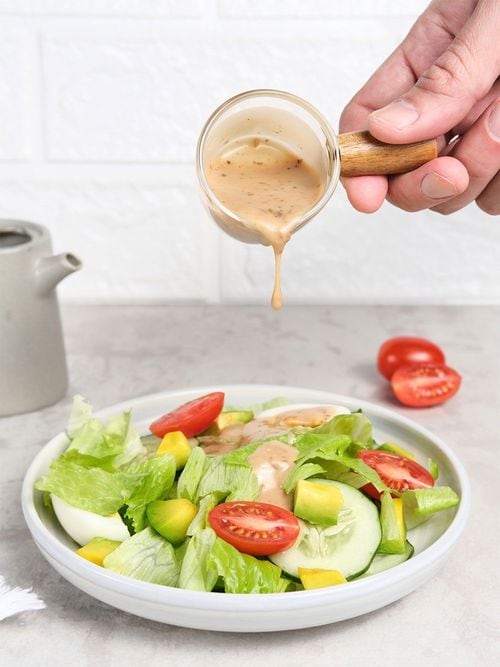 サラダにドレッシングをかける人の手