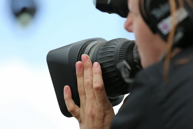 テレビカメラを抱えて撮影するカメラマン