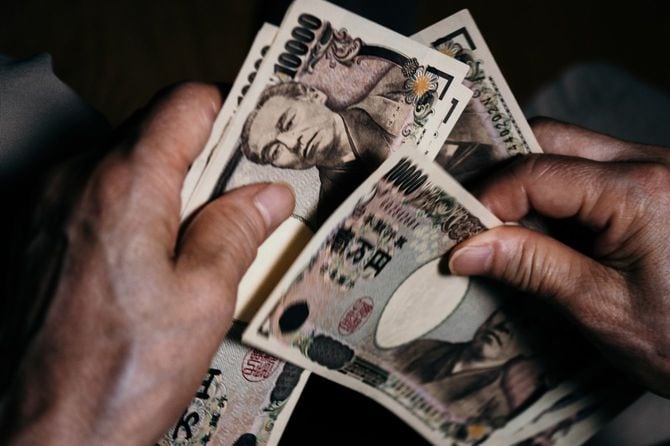 一万円札を両手で数えているシニアの手元