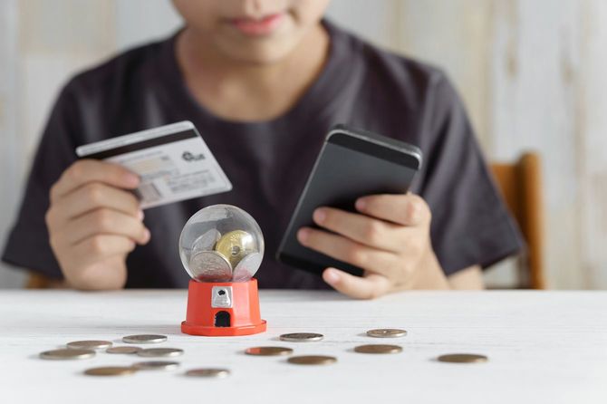 小学生男子がクレジットカードとスマホを持ち、課金しようとしている