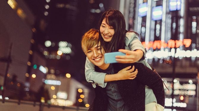 男性におんぶしてもらいながら自撮りする女性