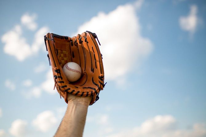 青空の下、しっかりボールをキャッチしたグローブをはめた手