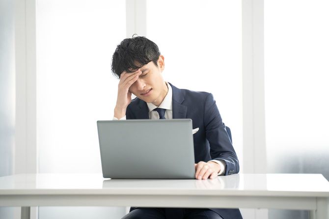 PCを見ながら頭を抱えている男性