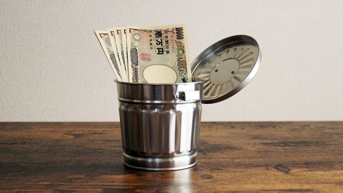 ミニチュアのごみ箱に入れられた一万円札