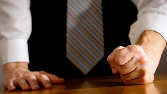 拳を机に打ち付けるビジネスパーソン