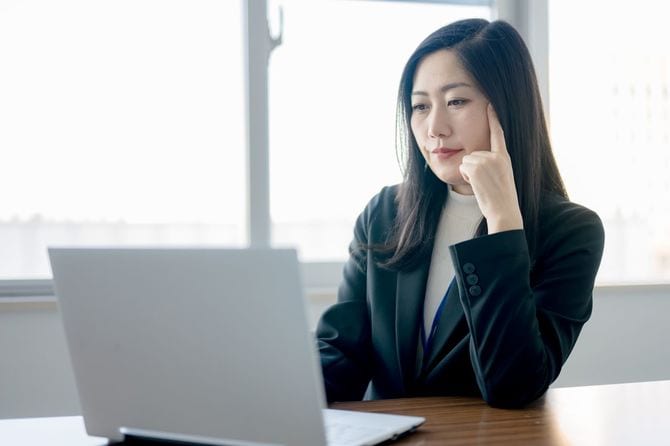 PCを前に思案するビジネスウーマン