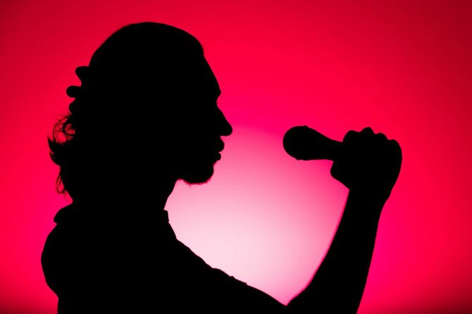 マイクを持って歌う人のシルエット