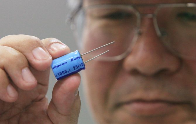 トヨタ自動車の品質監査棟で行われる人材育成過程の説明で、コンデンサを手にする作業員。同社の「現地現物」主義にのっとり、各種の部品を用いて人材育成を行う＝2010年3月30日、愛知・豊田市の同社本社