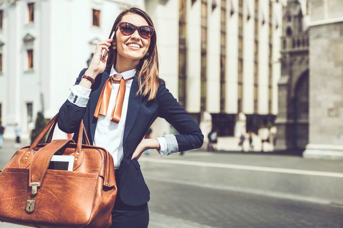 笑顔のラテン系ビジネスウーマンはカバンを手に通話中