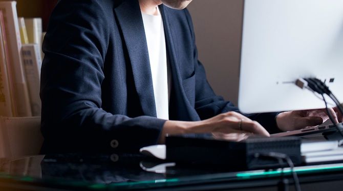 在宅でデスクトップPCで働く日本人男性