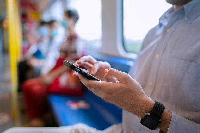 公共交通機関で携帯電話を使用するビジネスマン