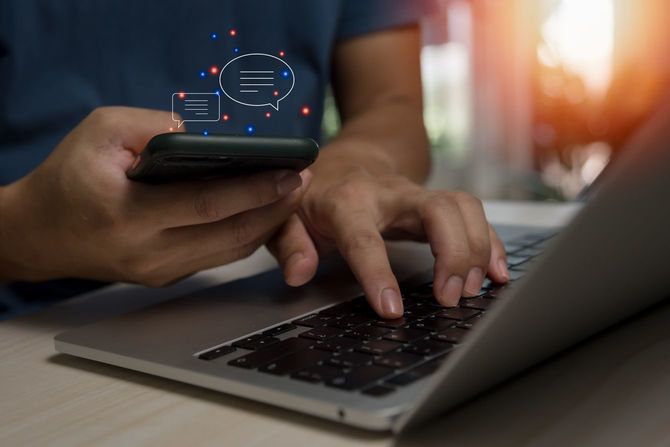 スマホ片手にノートパソコンを使用する人の手元