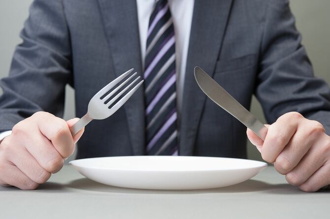 ナイフとフォークを持っている日本人ビジネスマンの手