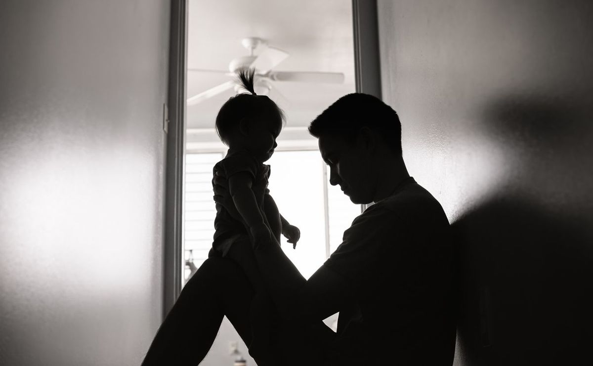 家の廊下で赤ちゃんを抱き上げる落ち込んだ父親