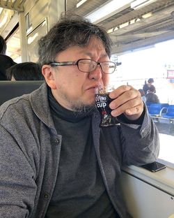 旅先で飲むお酒も大好き。移動中の電車でカップワインをキューっと。