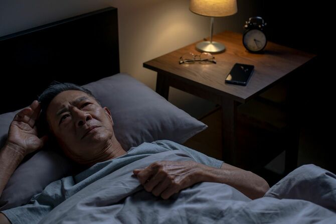ベッドに横たわる不眠症の男性