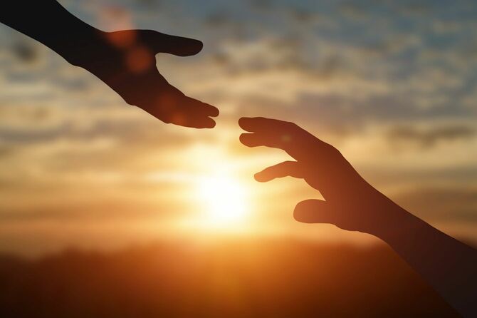 日没の背景に手を伸ばし、助けの手を差し伸べる