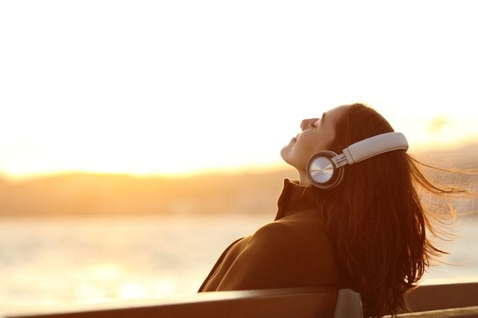 冬の日、ベンチに座り、ヘッドホンで音楽を聴いている女性