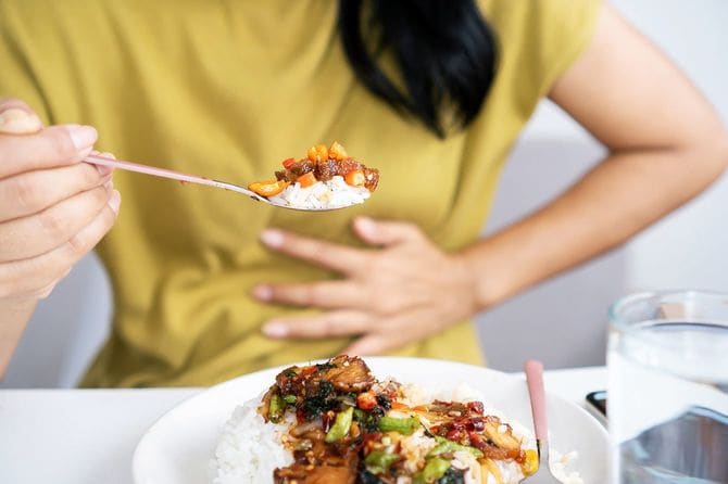 スパイシーな料理を食べお腹を押さえる女性