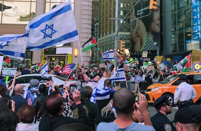 2023年10月13日、ニューヨークでイスラエルの国旗を掲げる人たち（左手前）。道路を挟んで向こう側は抗議活動を行うパレスチナ支持の人々