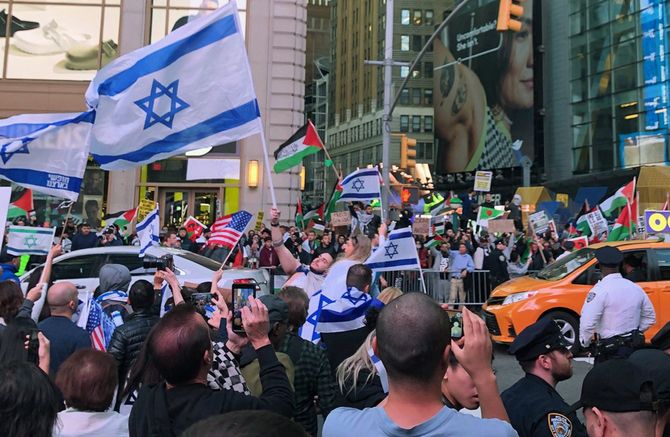 2023年10月13日、ニューヨークでイスラエルの国旗を掲げる人たち（左手前）。道路を挟んで向こう側は抗議活動を行うパレスチナ支持の人々