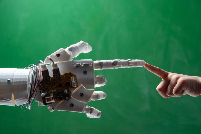 黒板の前でロボットと子供の指がE.T.みたいに指先触れ合っている