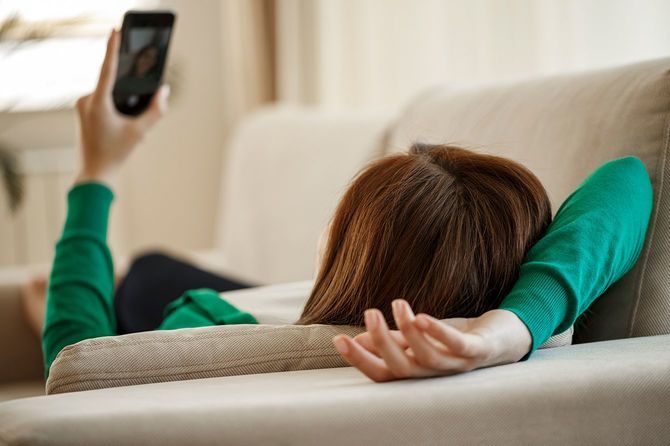 ソファーでスマホを眺める女性