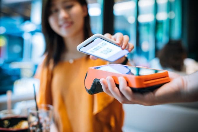 カフェでスマートフォンで支払う人