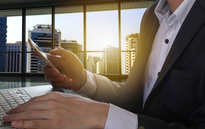 スマホとパソコンを使用するビジネスマン