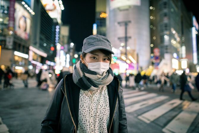 夜の都市をマスク着用で歩く女性
