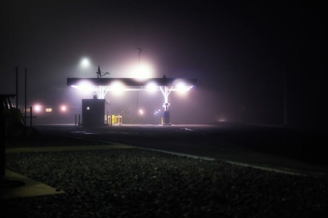 11月下旬の深夜、霧のかかった人けのないガソリンスタンド