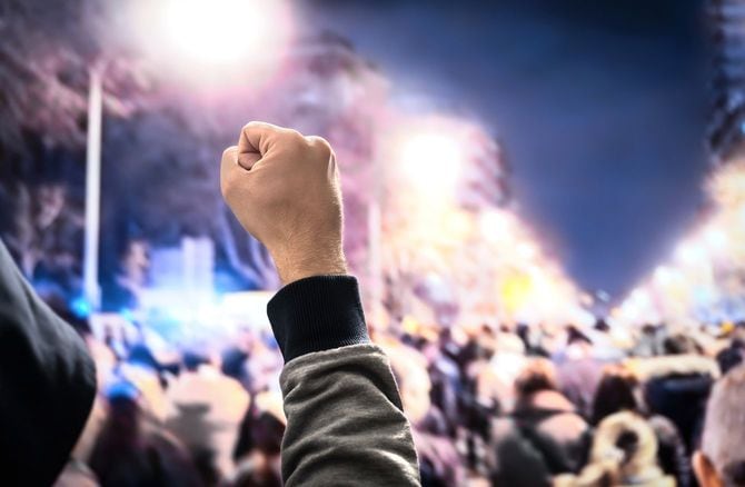 デモ行進で拳をあげて歩く人