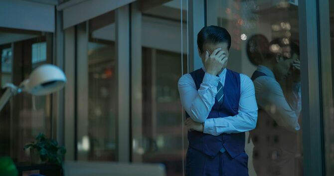 薄暗いオフィスで苦悩する中年のビジネスマン